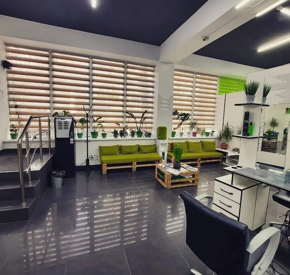 Zona de așteptare de la Beauty Life Salon, cu canapele verzi și plante